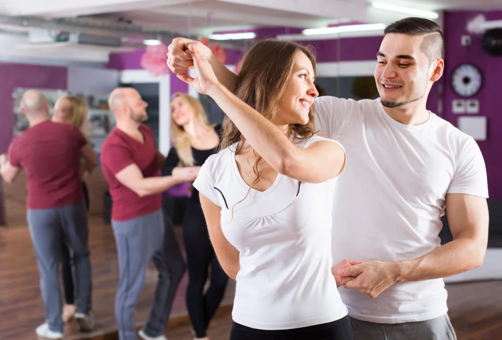 Confident couple dancing together after lessons in The Woodlands TX smiling and connected on dance floor